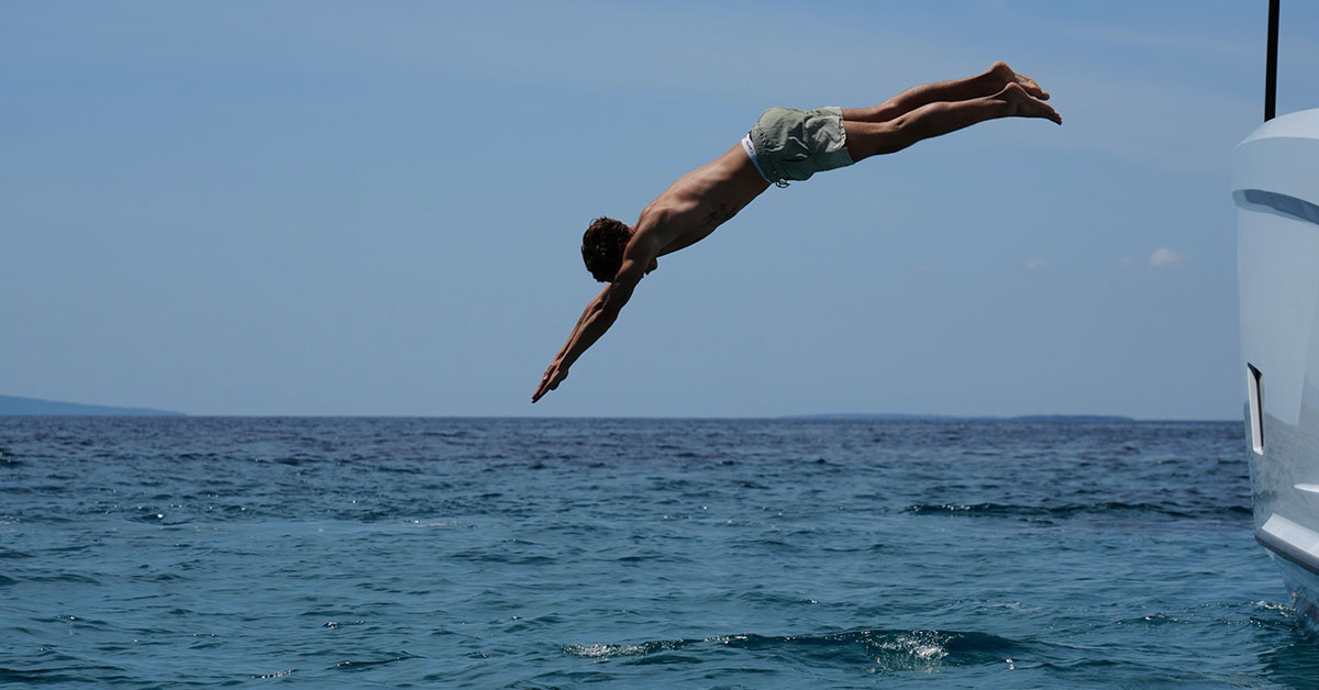 persona saltando al agua desde barco boating